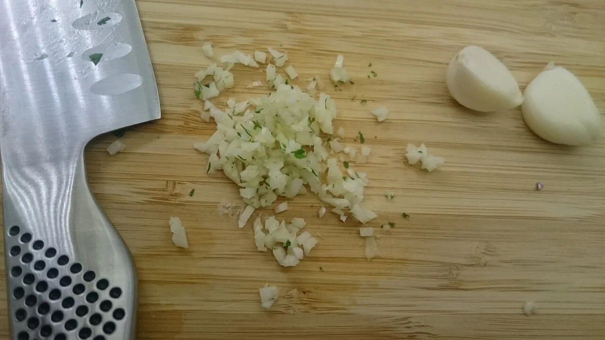 도마 위에서 잘게 다진 마늘과 마늘 쪽